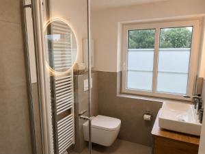 a bathroom with a toilet and a sink and a window at elf-36 Apartmenthaus Bensersiel in Bensersiel +29 photos