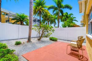 a patio with a chair and a fence and palm trees at Barefoot Beach Resort F104 in Clearwater Beach