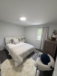 a white bedroom with a bed and a chair at Crewe Corner D in Crewe