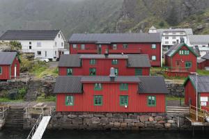 a group of red houses in a town with mountains at The traditional Burekka 17 - Lofoten in Stamsund