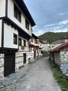 an alley in a village with stone buildings at Валериевата Къща 2 in Shiroka Laka +3 photos