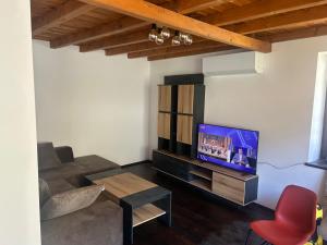 a living room with a tv and a red chair at Валериевата Къща 2 in Shiroka Laka