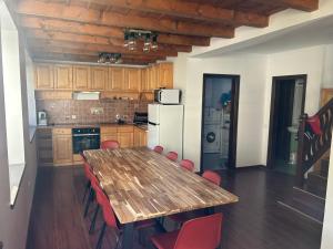 a kitchen with a wooden table and red chairs at Валериевата Къща 2 in Shiroka Laka