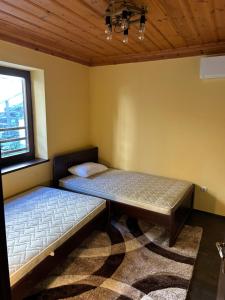 a bedroom with two beds and a window at Валериевата Къща 2 in Shiroka Laka