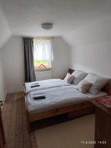 a bedroom with a bed with white sheets and a window at Chalupa Meduňka in Vsetín