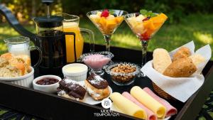 a tray of food with desserts and drinks on a table at Bollté Praia Boutique Pousada - Campeche - Floripa - SC in Florianópolis