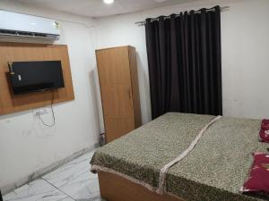 a bedroom with a bed and a tv and a cabinet at Hotel Tokyo in Bathinda +2 photos