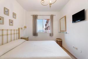 a bedroom with a bed and a television and a window at Residencial La Gomera in Puertito de Güímar +19 photos