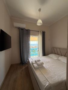 a bedroom with a large bed and a window at Yamas Hotel "Ex Malibu" in Dhërmi
