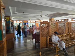 a man sitting on a bench in a restaurant at Hotel Mashabrum Skardu Free Breakfast Mountain View Family Rooms & Free WiFi in Skardu