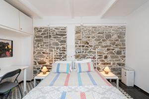 a bed in a room with a stone wall at Με συμπάθεια-With sympathy - private parking in Kavála