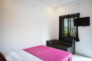 a bedroom with a pink bed and a black chair at Vagamon leafhill mountain view holidays in Vagamon