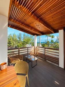 a porch with a wooden roof with chairs and a table at Cote Plage in La Saline les Bains