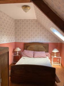 a bedroom with a bed with pink walls and two lamps at GITE EQUESTRE DE LA LANDE in Bréhal