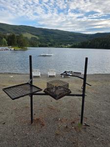 a grill on the shore of a lake with a boat at 1 sleeping room in Fagernes