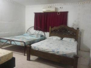 a bedroom with two beds and a red curtain at Reina Elizabeth I in Santa Marta +3 photos