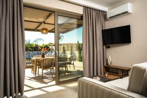 a living room with a couch and a television and a table at Alpha Waves By Banana Beach in Vasilikos