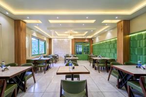 a restaurant with wooden tables and green walls at Treebo Belita Resort Munnar With Infinity Pool in Munnar