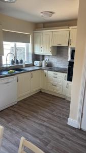 a kitchen with white cabinets and a wooden floor at Deel Manor in Eas Géitine