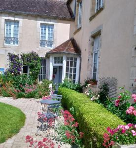 a house with a table and flowers in front of it at Gîtes de france le cosy saint pierre in Sées