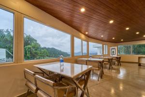a dining room with tables and chairs and windows at Treebo Belita Resort Munnar With Infinity Pool in Munnar