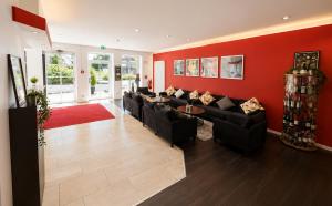 a living room with black couches and a red wall at DORMERO Hotel Werther in Werther
