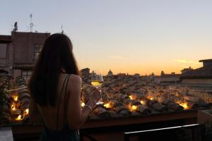 a woman standing on a balcony with a glass of wine at Hotel Caravita in Rome