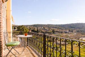 a table and a chair on a balcony with a view at Vlychos Olympi Lodges - Chios Cozy Getaways in Olýmpoi
