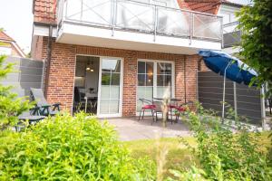a house with a balcony and a table and chairs at Ferienwohnung Hoffmann in Hooksiel