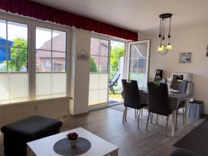 a living room with a table and chairs and windows at Ferienwohnung Hoffmann in Hooksiel