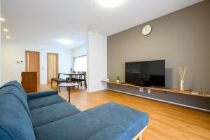 una sala de estar con un sofá azul y un televisor en KOAのお宿 ー Koa no Oyado ー, en Gujō