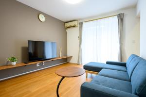 una sala de estar con un sofá azul y un televisor en KOAのお宿 ー Koa no Oyado ー, en Gujō