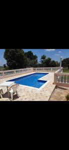 a swimming pool with two white chairs next to a fence at Chácara com piscina no condomínio Vitassay in Boituva