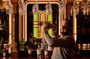 a man standing at a bar with a bottle in his hand at The Tynemouth Castle Inn - The Inn Collection Group in Tynemouth
