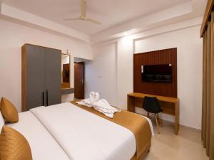 a bedroom with a bed and a desk and a television at Nova Alhind Airport Hotel Cochin in Nedumbassery +2 photos
