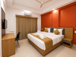 a bedroom with a bed and a desk and a television at Nova Alhind Airport Hotel Cochin in Nedumbassery