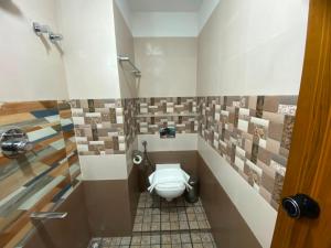 a bathroom with a toilet in a room with pictures on the wall at Nova Alhind Airport Hotel Cochin in Nedumbassery