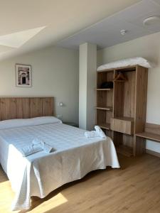 a bedroom with a large white bed and wooden floors at Apartamentos El Jardín de Isla Autocheck-In in Isla
