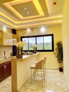 a kitchen with a counter with two chairs and a window at Logements Majeo in Kribi