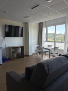 a living room with a couch and a table and chairs at Apartamentos El Jardín de Isla Autocheck-In in Isla