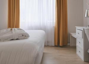 a bedroom with a bed and a dresser and a window at Le Royal Picardie, BW Signature Collection in Albert