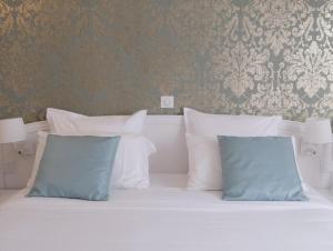 a white bed with two blue pillows on it at Le Royal Picardie, BW Signature Collection in Albert