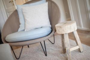 a chair with a pillow and a wooden stool at Seepferdchen in Keitum