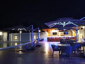 a patio with tables and chairs and umbrellas at night at Logements Majeo in Kribi