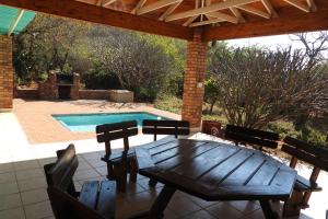 a wooden table and chairs on a patio with a pool at Hide Away Wedding,Conference & Function Venue in Bela-Bela