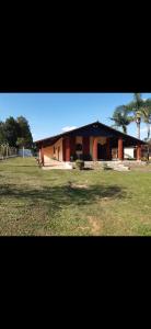a building with a grass field in front of it at Chácara com piscina no condomínio Vitassay in Boituva