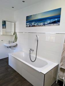 a white bathroom with a bath tub and a sink at Chez D&D Plus in Eschweiler