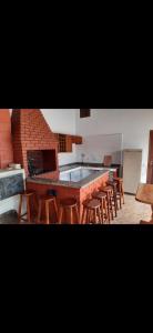 a kitchen with wooden stools and a large counter top at Chácara com piscina no condomínio Vitassay in Boituva