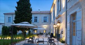 a patio with tables and chairs and an umbrella at Hotel College des Doctrinaires, BW Premier Collection in Lectoure