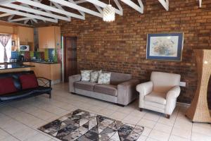 a living room with couches and chairs and a brick wall at Hide Away Wedding,Conference & Function Venue in Bela-Bela